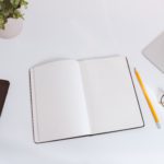 White work table with notes, smartphone and laptop